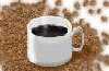 A steaming cup of coffee nested in roasted beans.